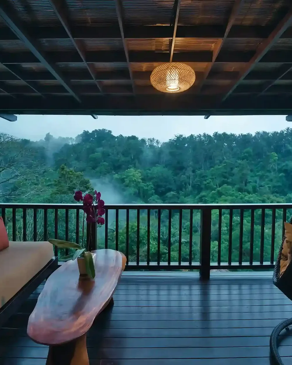 View from a covered wooden deck over a misty jungle valley in the early morning near Ubud, Bali
